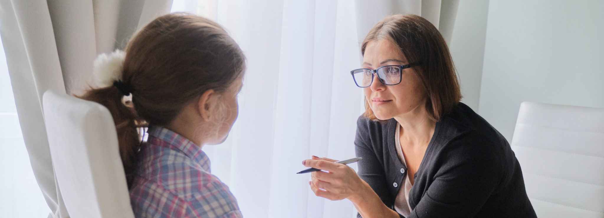 Woman social worker talking to girl. Child psychology, mental health