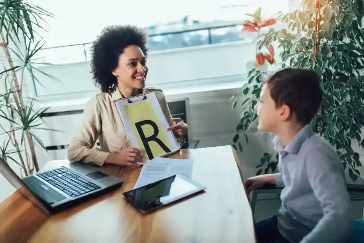 A speech-language pathologist works with a young disfluency client.